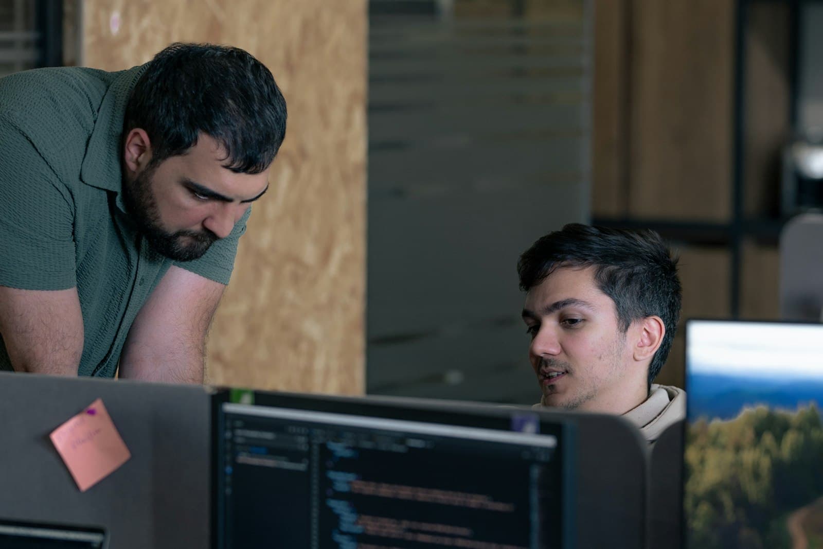 Two developers reviewing code together on a monitor in an office